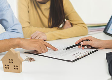 Real estate law consultation with a miniature house model through legal paperwork in an office